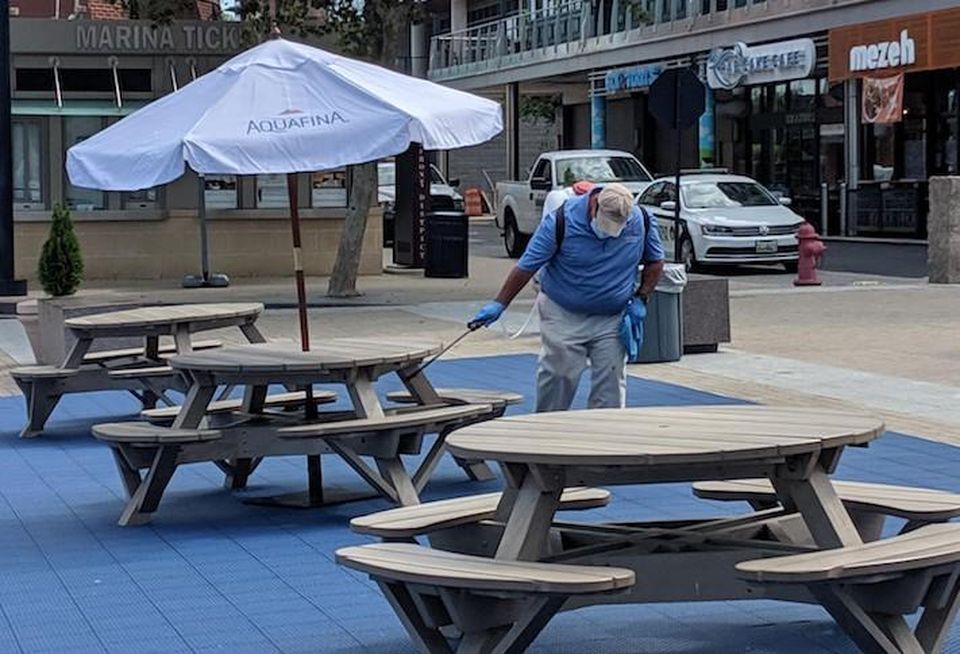 A National Harbor employee cleaning tables in the public plaza.