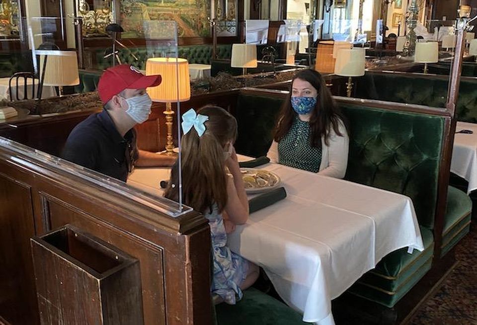 Customers dining inside Old Ebbitt Grill, where Clyde's Restaurant Group installed plexiglass barriers between tables.