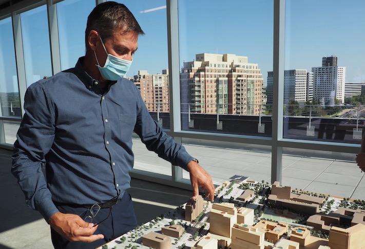 Federal Realty CEO Don Wood, standing in the top floor of the new 909 Rose office building, pointing at a model of the Pike & Rose development. 