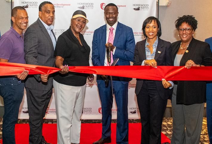 Frontier Development's Evens Charles, flanked by business partners and local officials, cutting the ribbon on a Homewood Suites hotel in Maryland. 