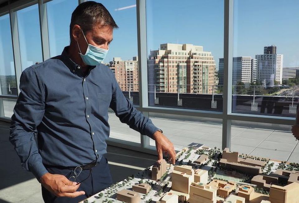 Federal Realty CEO Don Wood, standing in the top floor of the new 909 Rose office building, pointing at a model of the Pike & Rose development.