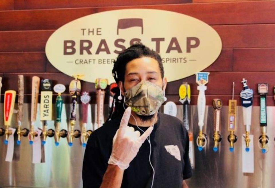 A bartender wearing a mask and gloves at The Brass Tap in National Harbor.