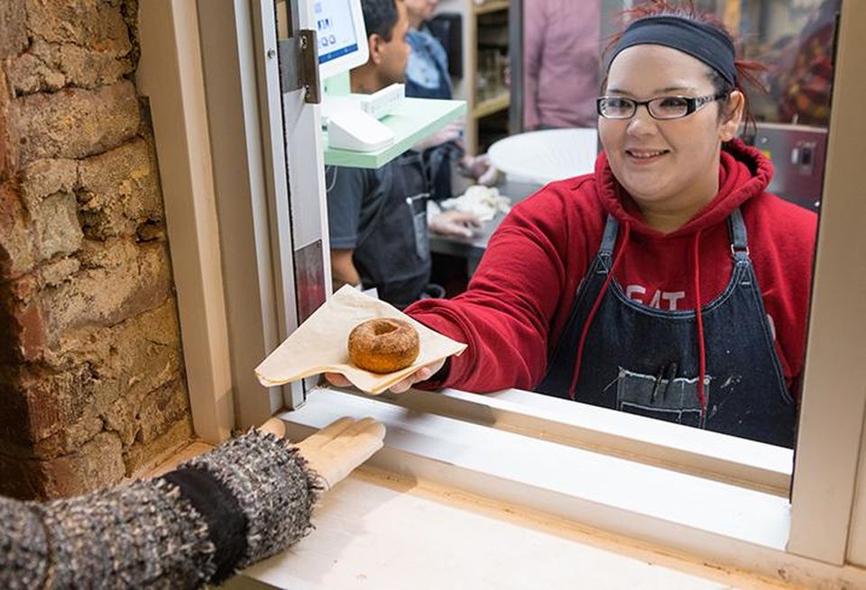 Stormy Gallant hands a customer a cinnamon sugar doughnut at Reigning Doughnuts. Sometimes up to four employees occupy 90 SF of space, which owner Jeff Tonidandel says can make for tricky logistics.