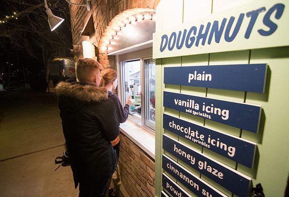 Customers order doughnuts via a walk-up window on the sidewalk at Reigning Doughnuts.