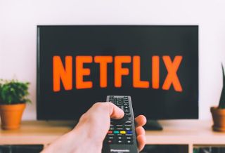 Photo of person pointing remote at the Netflix logo on a television