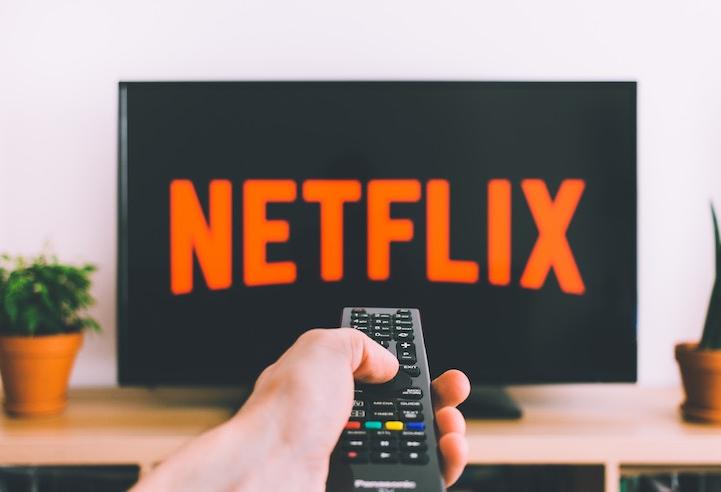 Photo of person pointing remote at the Netflix logo on a television