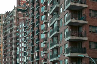 Row of tall brick apartment buildings with numerous balconies, windows, and varying architectural styles.