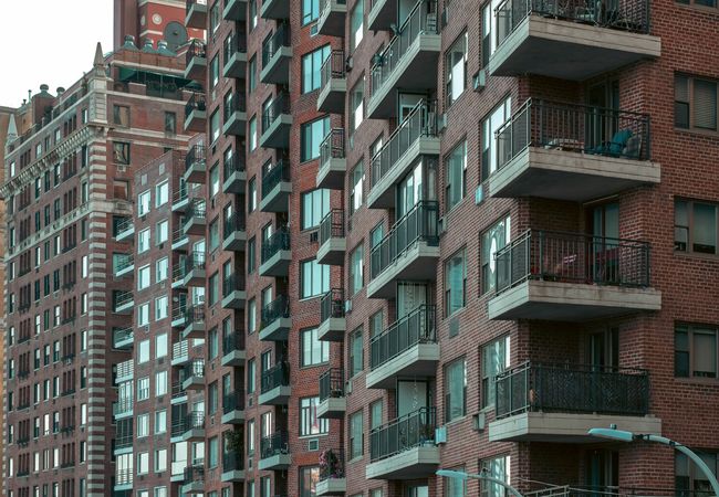 Row of tall brick apartment buildings with numerous balconies, windows, and varying architectural styles.