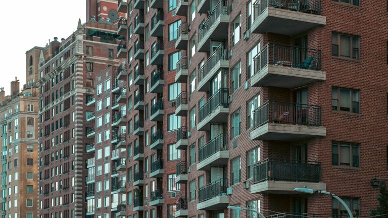 Row of tall brick apartment buildings with numerous balconies, windows, and varying architectural styles.