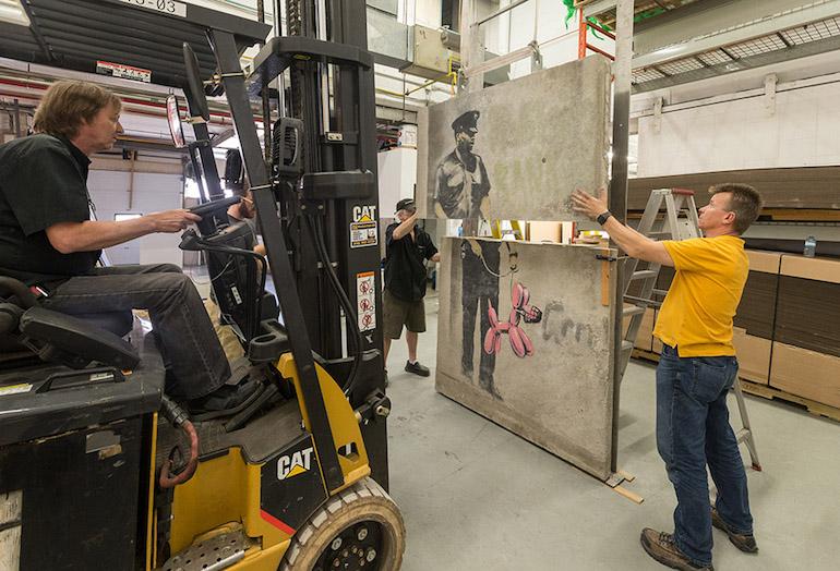 Crews work on the restoration of the Banksy panels that would be installed at One York.