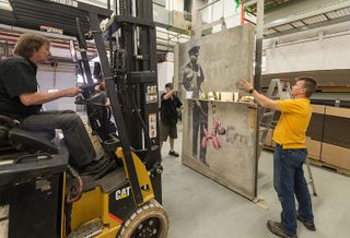 Crews work on the restoration of the Banksy panels that would be installed at One York.