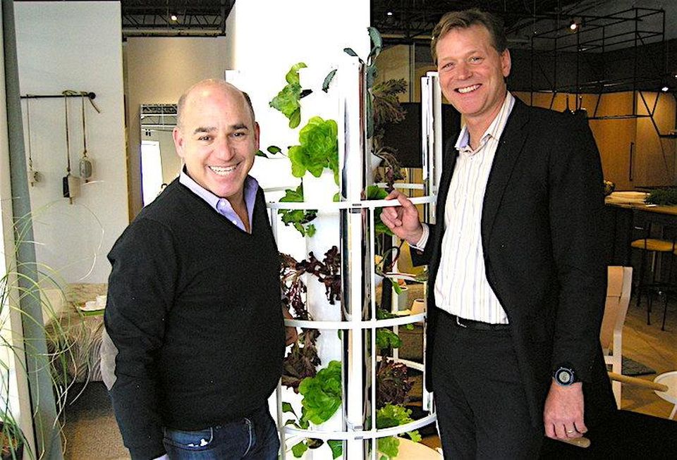 Curated Properties partner Adam Ochshorn and Windmill Developments CEO Jonathan Westeinde pose with a LED-lit aeroponic planter tower, available to owners at The Plant