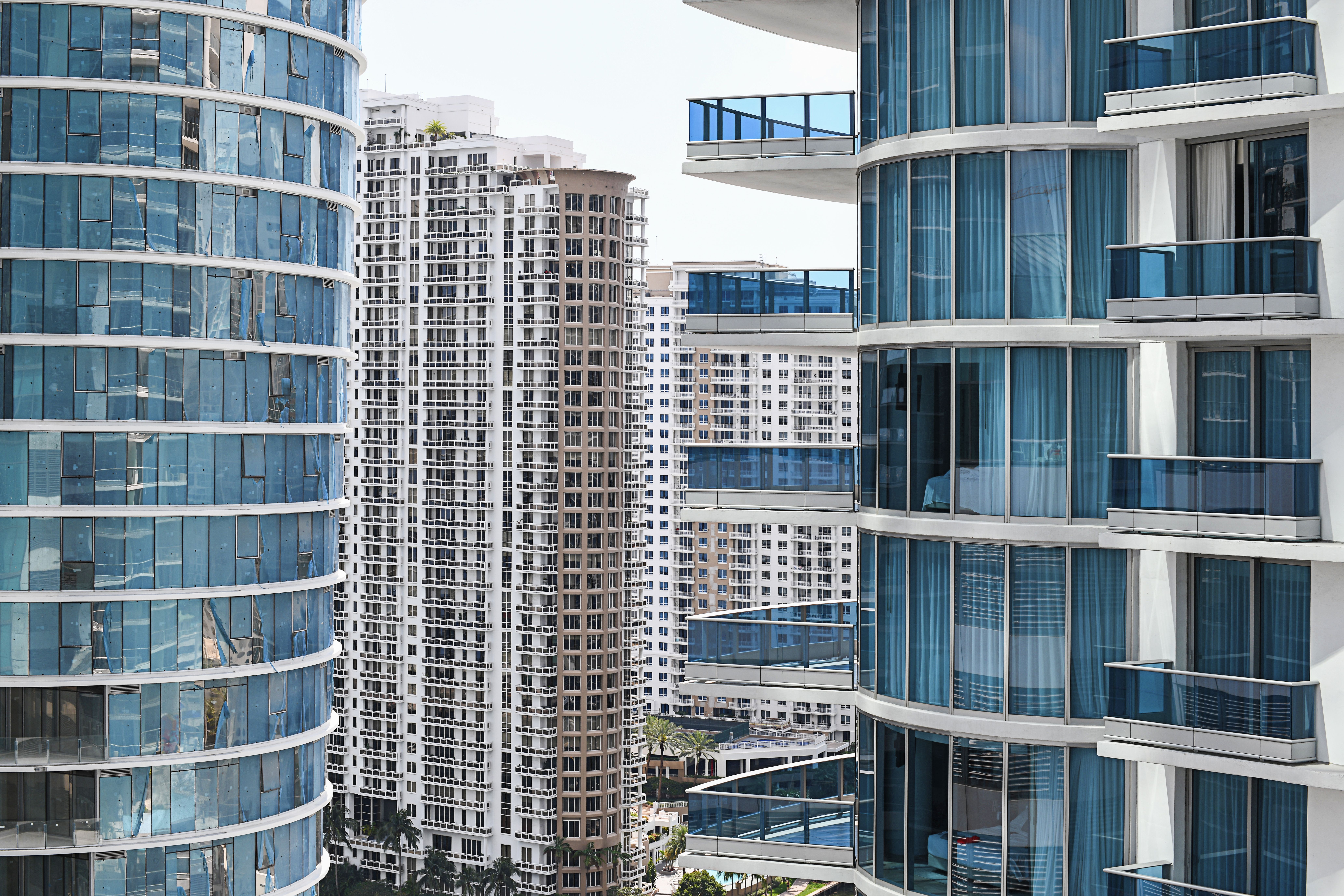 Modern high-rise buildings with glass balconies and blue-tinted windows under a clear sky.
