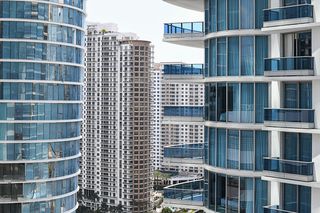 Modern high-rise buildings with glass balconies and blue-tinted windows under a clear sky.