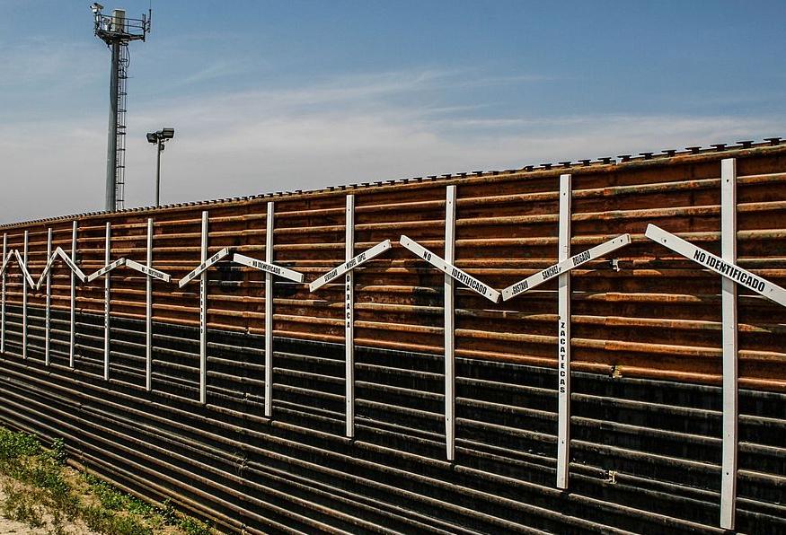Mexico–United States barrier at the border between Tijuana and San Diego, with surveillance tower in the background.  The crosses represent migrants who died in the crossing attempt, some identified, some not. 