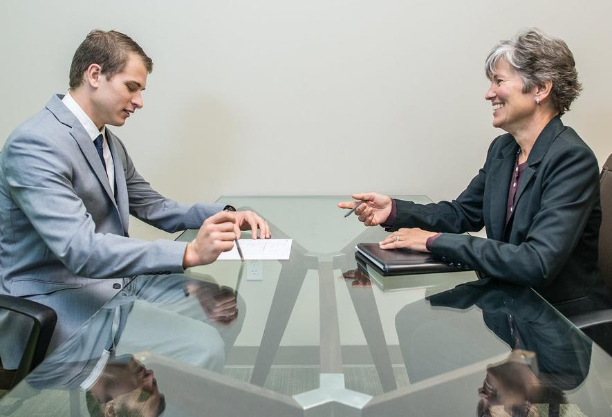 An interviewer and interviewee during a job interview in a sparsely decorated conference room.