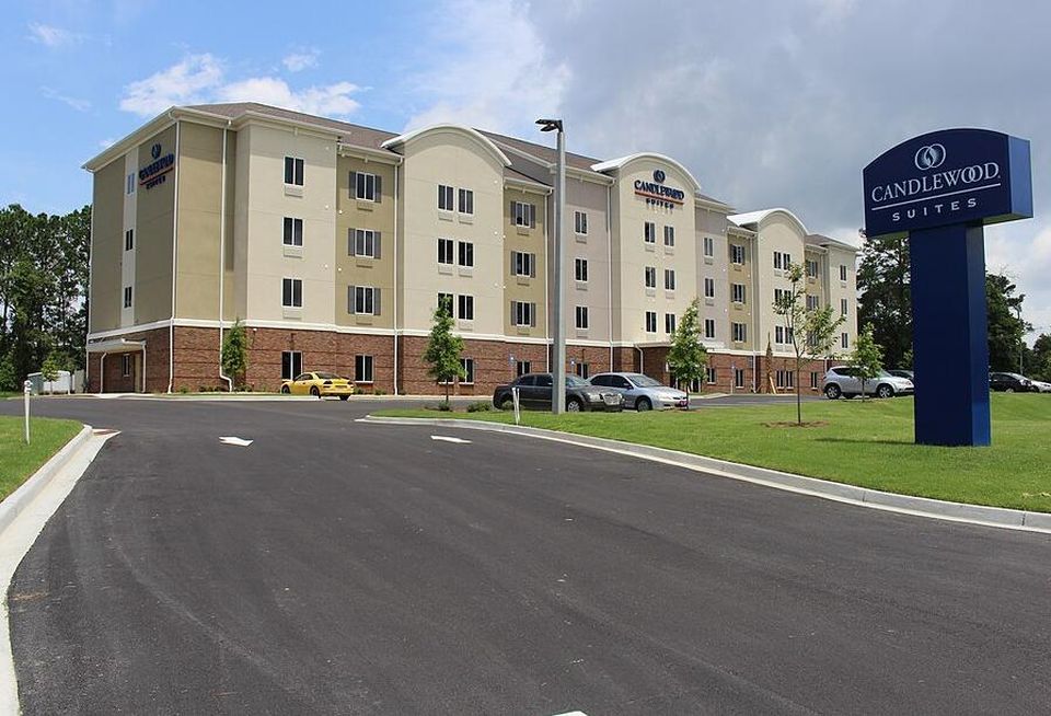 A photograph of a Candlewood Suites location in Valdosta, Georgia, on a sunny day with few cars parked outside.