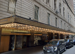 Exterior of the Palmer House with a lit marquee and several parked black SUVs along the street.