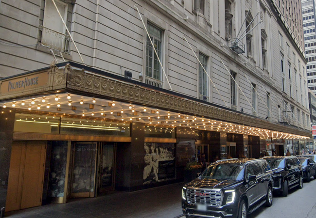 Exterior of the Palmer House with a lit marquee and several parked black SUVs along the street.