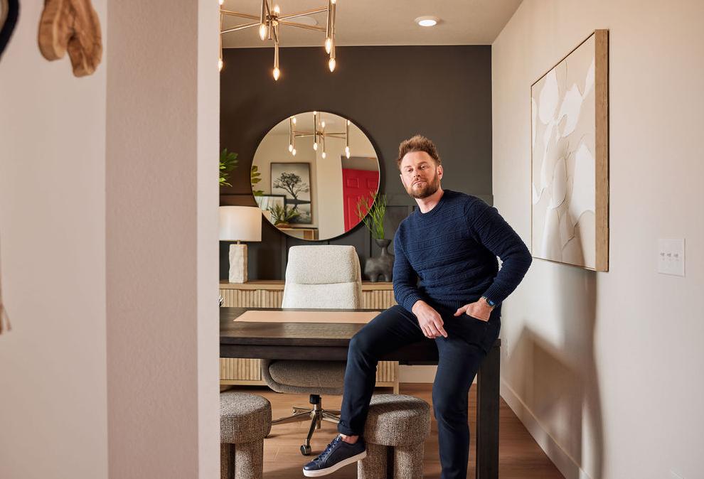 A photograph of Bobby Berk posing in the dining room of a staged model of Tri Pointe Homes newest community.
