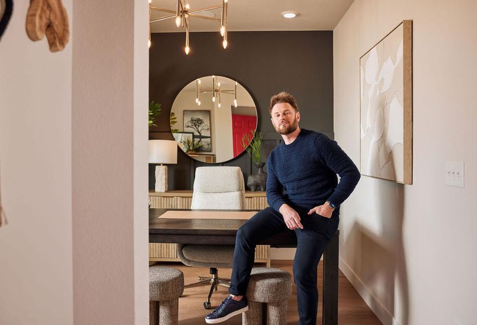 A photograph of Bobby Berk posing in the dining room of a staged model of Tri Pointe Homes newest community.