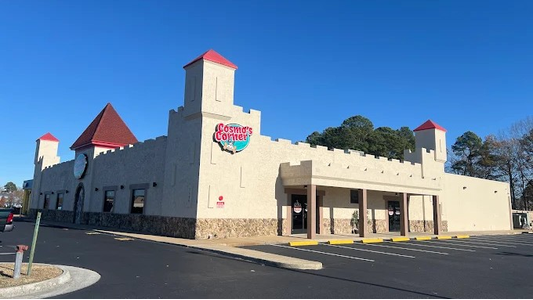 Cosmo Corner's building with towers and red roofs, featuring a sign that reads "Cosmic's Corner" against a clear blue sky.