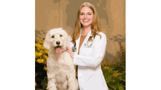 Dr. Leslie Stinson Serrano -Associate Veterinarian standing next to a happy, fluffy white dog with its tongue out