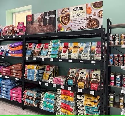 A well-stocked retail shelf displaying various bags of Acana brand dry dog food