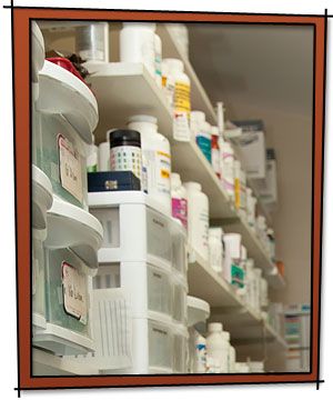 Pet Pharmacy shelves filled with various containers and bottles of medical supplies and medications, organized in a pharmacy or storage room.