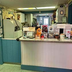 A reception counter in an office with various papers, brochures, and small items. Blue and white decor with a doorway leading deeper into the office.