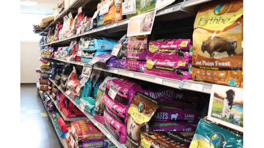 K9 Kaos offering various brands and colorful packages of pet food stacked on shelves.