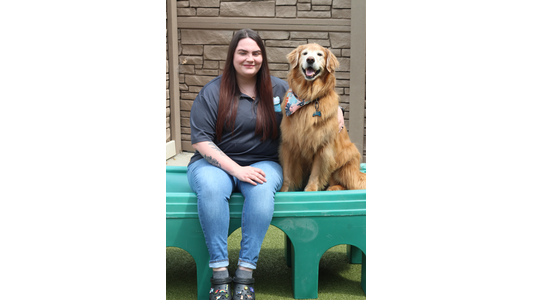 Tiff -CSR Shift Lead itting next to a happy Golden Retriever on a green plastic play structure.