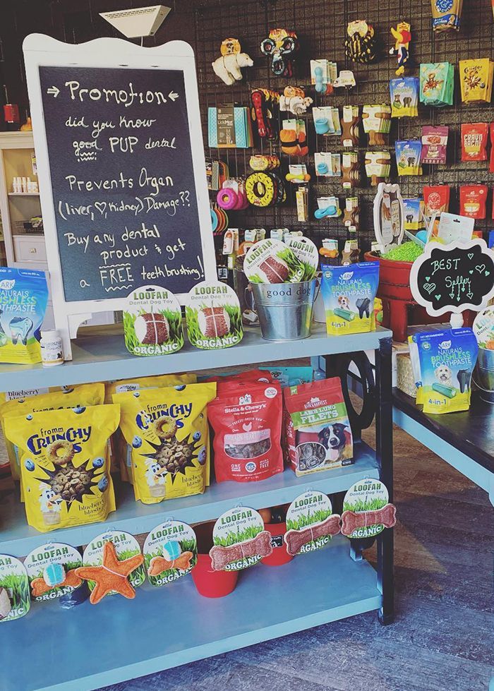K-9 Pet store display with shelves of dog treats and dental products. A chalkboard promotes a free toothbrush offer with purchase.