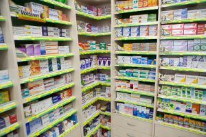 Pharmacy shelves filled with various medications, boxes of different colors and sizes, neatly organized and labeled with yellow tags.