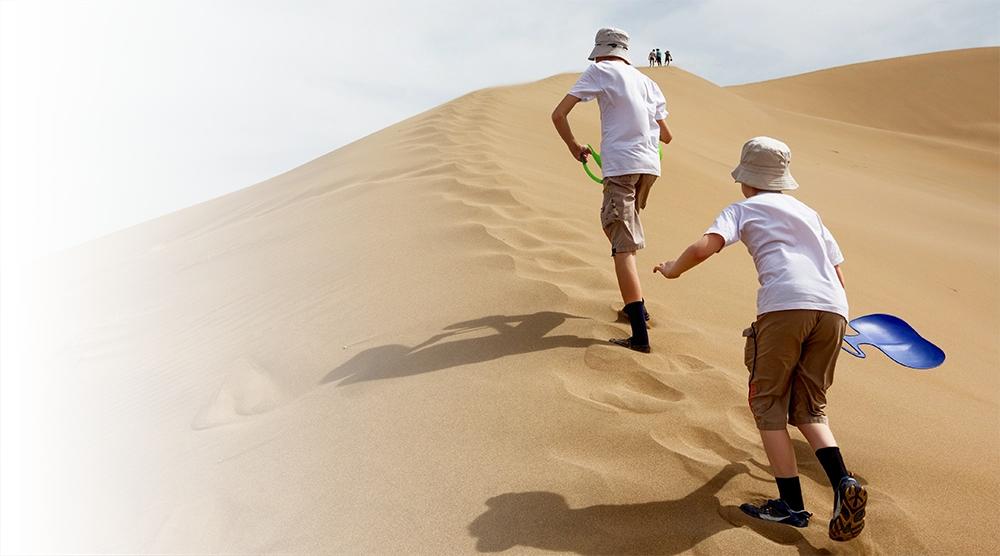 Two teens running down a sand dune in Israel
