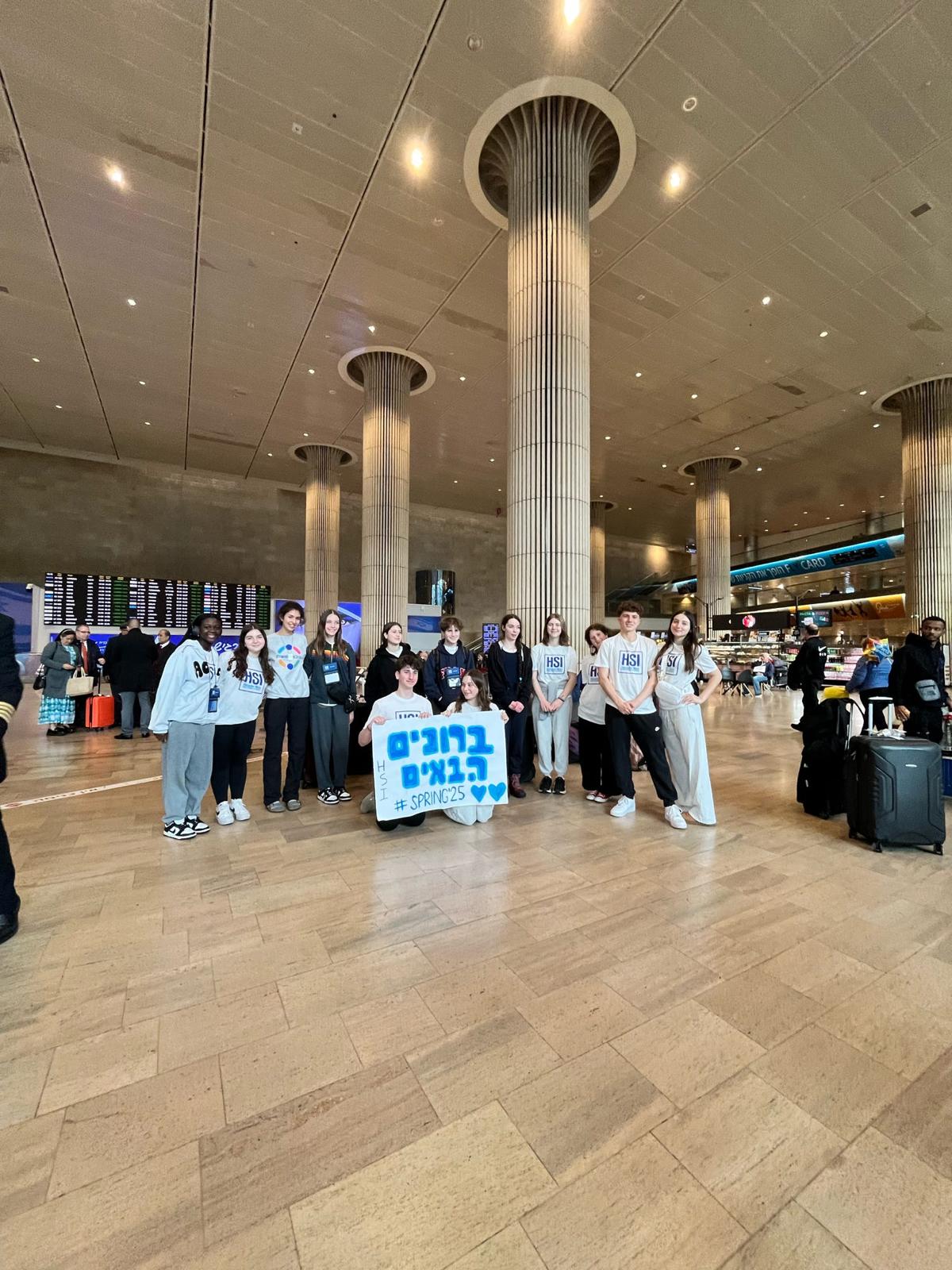 Group of HSI students holding a welcome sign at the airport