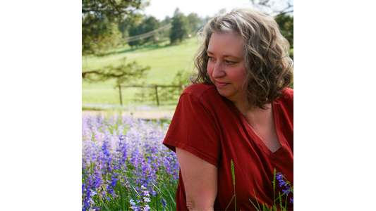 Casey in red shirt in front of flowers