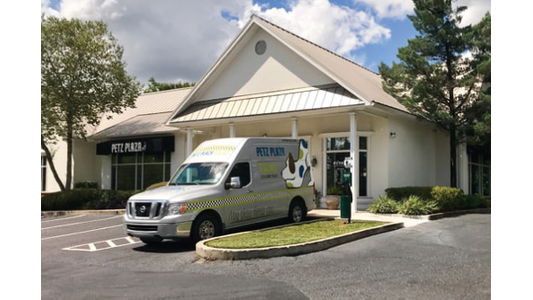 Petz Plaza pet taxi van parked outside a dog boarding and daycare facility storefront