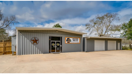 Exterior view of a gray metal building for a dog daycare and boarding facility, with glass entrance doors, garage doors, and a decorative star on the wall