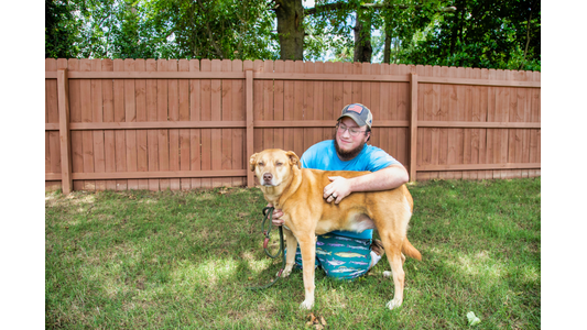 Endless Love Pet Palace  kneels on a grassy lawn, hugging and petting