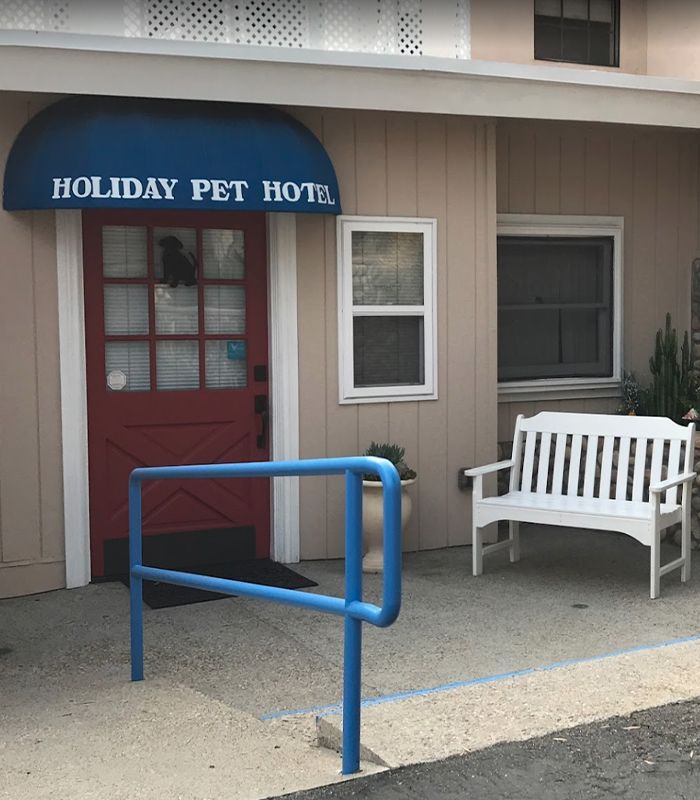 Front entrance of Holiday Pet Hotel with a blue awning, red door, and white bench